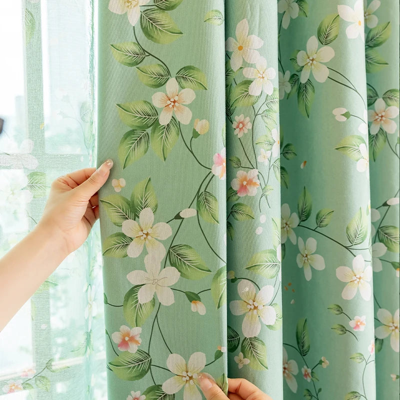 Light mint green curtains with a floral pattern are shown being held near a window.