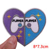 Two heart-shaped embroidered patches featuring a white game controller design with the word PLAYER on each half