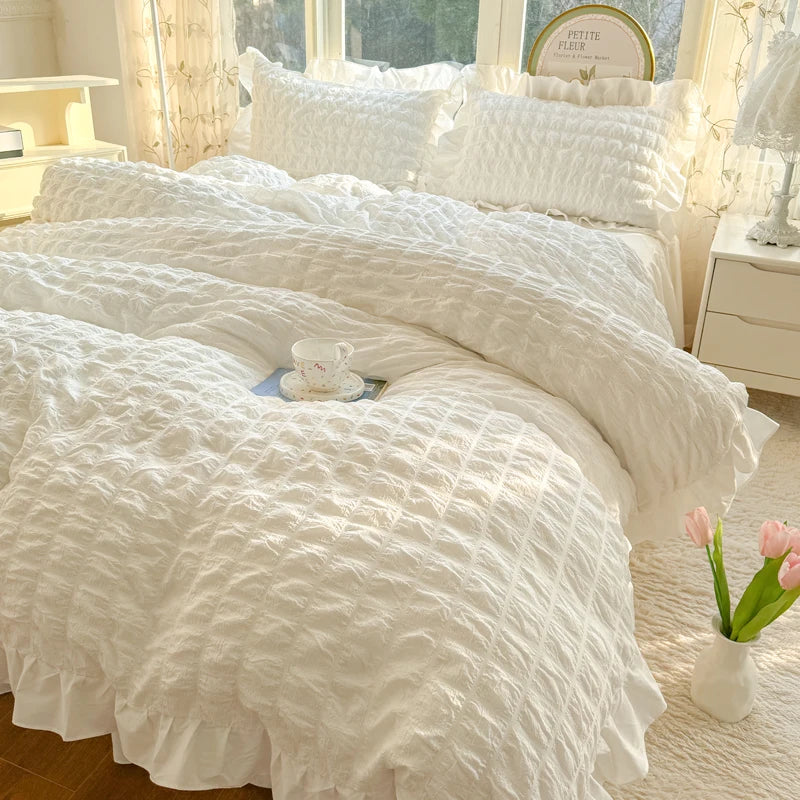 White lace seersucker duvet cover set displayed on a bed with sheer curtains and a small teacup.