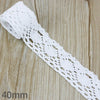 White cotton embroidered lace trim shown on a wooden surface.