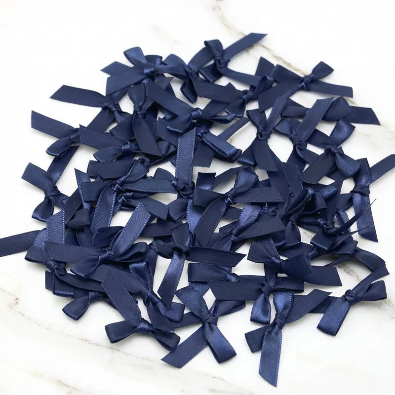 A pile of small navy blue satin ribbon bows for crafts and decor