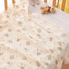A soft double-layer cotton baby swaddle blanket with a light beige pattern featuring small animal figures and orange accents.