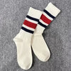 A pair of white crew socks with horizontal navy and red stripes on the leg