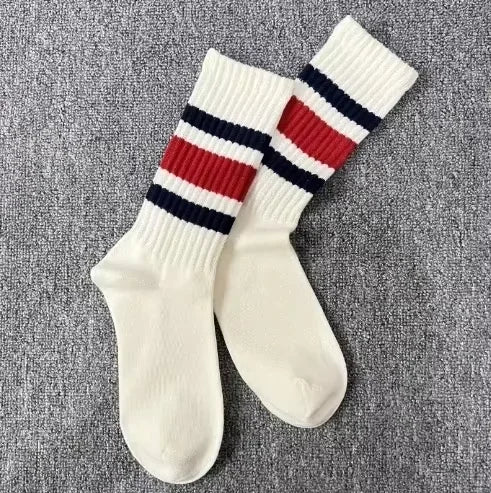 A pair of white crew socks with horizontal navy and red stripes on the leg