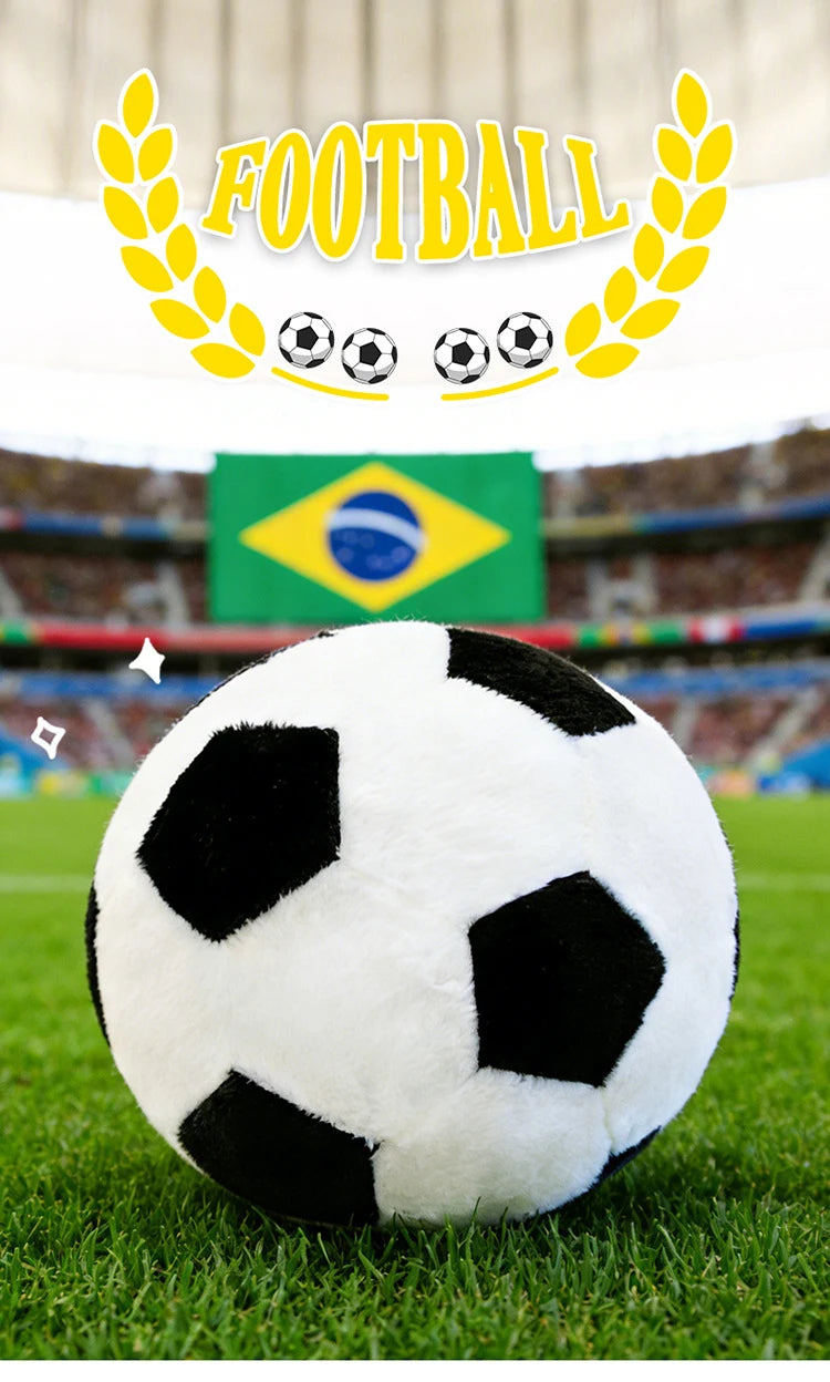 A white and black realistic football plush toy is centered on green grass with a Brazilian flag in the background.