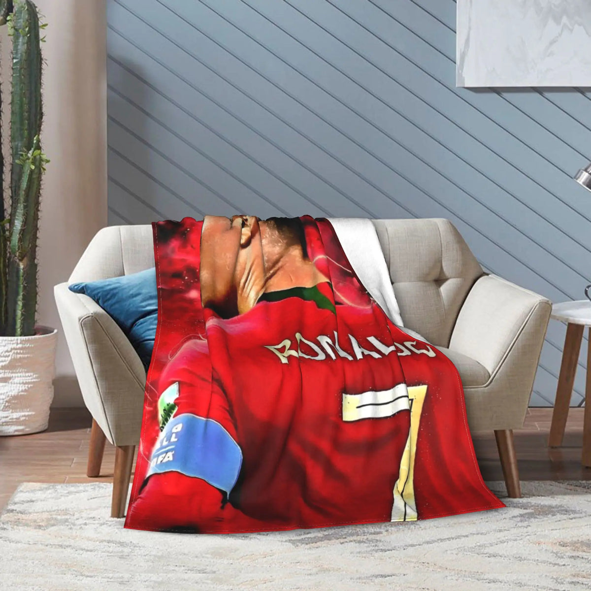 A red football jersey themed wool throw blanket draped over a light gray sofa.