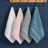 A set of four folded pure cotton face towels in white, pink, gray, and blue hanging from a wooden rack.