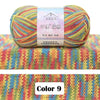A ball of multicolored 4-ply cotton knit yarn with a gradient pattern resting on a colorful knitted fabric background.
