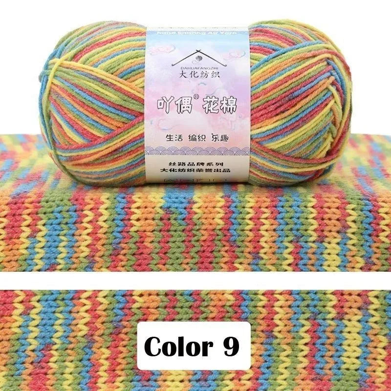 A ball of multicolored 4-ply cotton knit yarn with a gradient pattern resting on a colorful knitted fabric background.