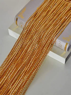 Golden beaded door string curtains laid out next to a book.