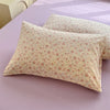 A light yellow floral printed pillow cover resting on a purple surface.