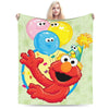 A person is holding a cartoon image of Elmo and Friends on a green flannel throw blanket.