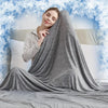 A woman is relaxing on a bed with a gray quilted blanket, surrounded by frosty blue decorative elements.