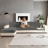 A modern gray sofa with white cushions and a fireplace in a living room setting.