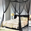 A bedroom featuring a dark wood bed draped with sheer black mosquito net curtains and floral bedding.