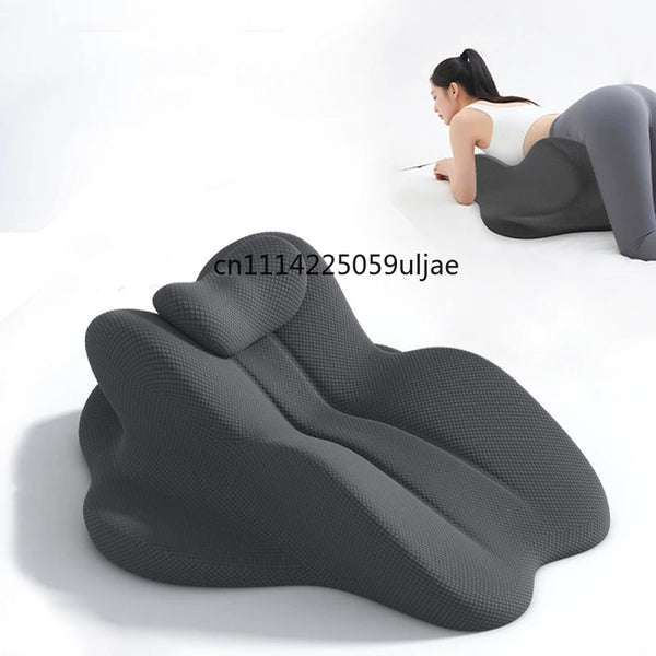 A dark gray ergonomic memory foam reading pillow is shown supporting a person's back and head for reading.