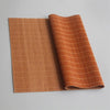 A rolled hand-woven bamboo tea mat in a warm orange color with vertical stripes.