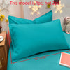 A teal pillowcase is displayed on a bed, with decorative star lights in the background.