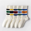 A set of white crew socks with horizontal stripes in black, yellow, green, blue, and orange.