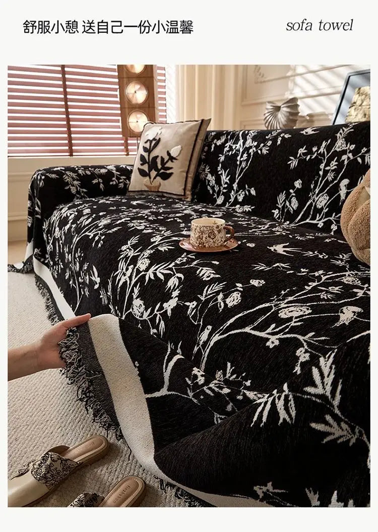 Black floral patterned sofa towel featuring white embroidery and a gold teacup on a bed.