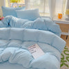 A light blue cotton bed linen set with pillows and a duvet is displayed on a bed.