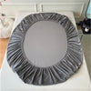 A round, gathered gray velvet frame for a mirror or artwork displayed on a white surface.