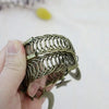 A hand holds a vintage star and moon metal curtain clip with an intricate coiled design.