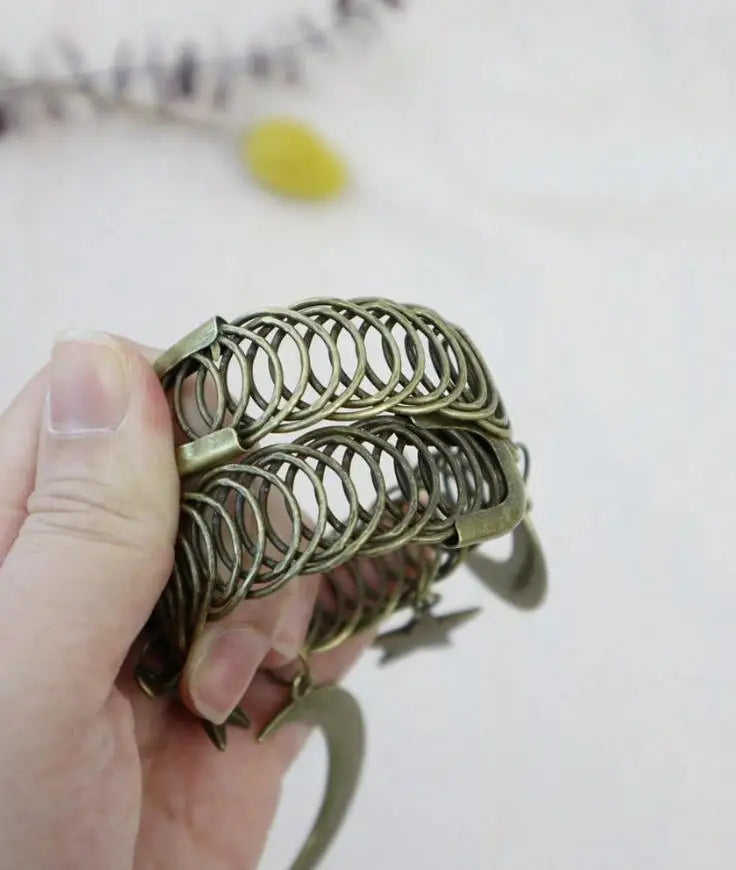 A hand holds a vintage star and moon metal curtain clip with an intricate coiled design.