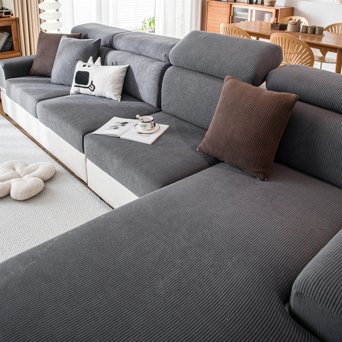 A gray removable jacquard seat cushion cover on a sofa with decorative pillows and a cup.