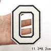 A white letter O patch with a black border is held in a hand.