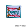 An embroidered letter patch with the text Prayer Changes everything in red and orange thread on a green fabric.