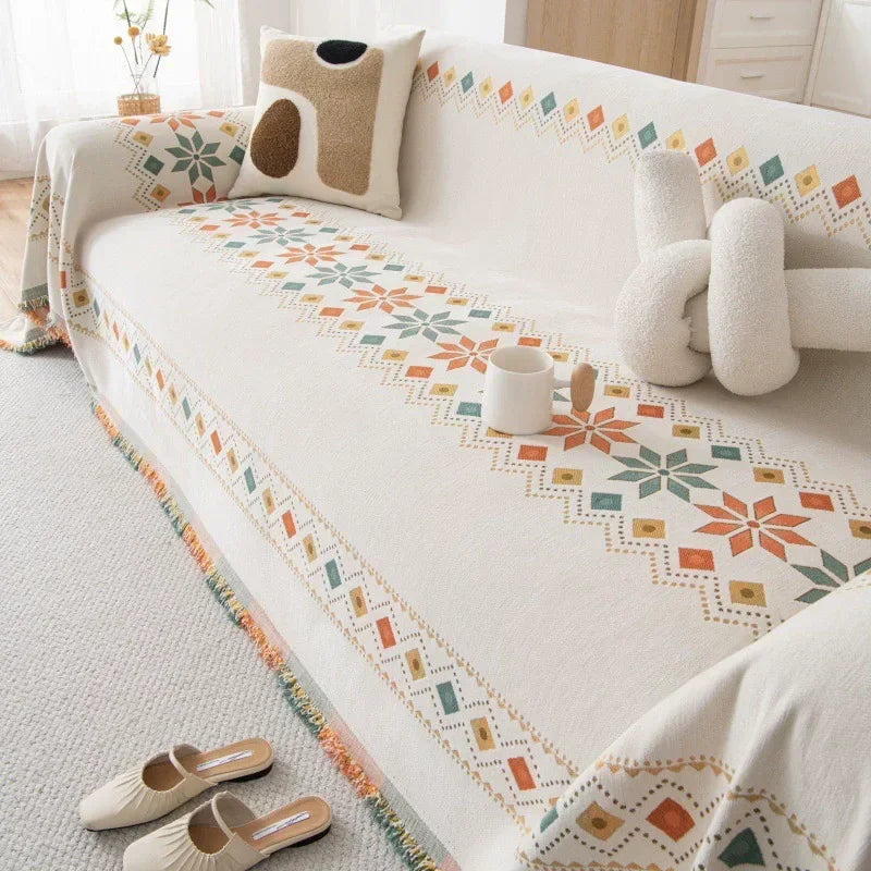 A cream accent sofa cover featuring a geometric floral pattern with orange, green, and beige accents.