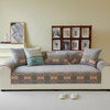 A beige sofa covered in patterned fabric, featuring a row of framed books on the wall.