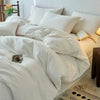 A white cotton yarn-dyed duvet cover is displayed on a bed with natural wood accents and a patterned rug.