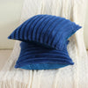 A stack of deep blue faux rabbit fur cushion covers resting on a white textured fabric.