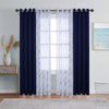 A set of navy blue blackout and sheer window drapes hanging on a rod in a bright room.