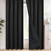 A floor-length black blackout curtain hanging from a rod, shown in a bright room.