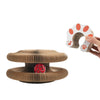 A hand holds a white cat paw-shaped item, next to a brown, textured scratching board with a red, speckled object inside.