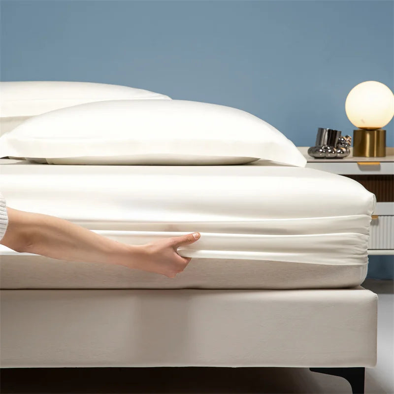 A hand gently adjusts a white luxury bamboo bedding set on a bed against a blue wall.