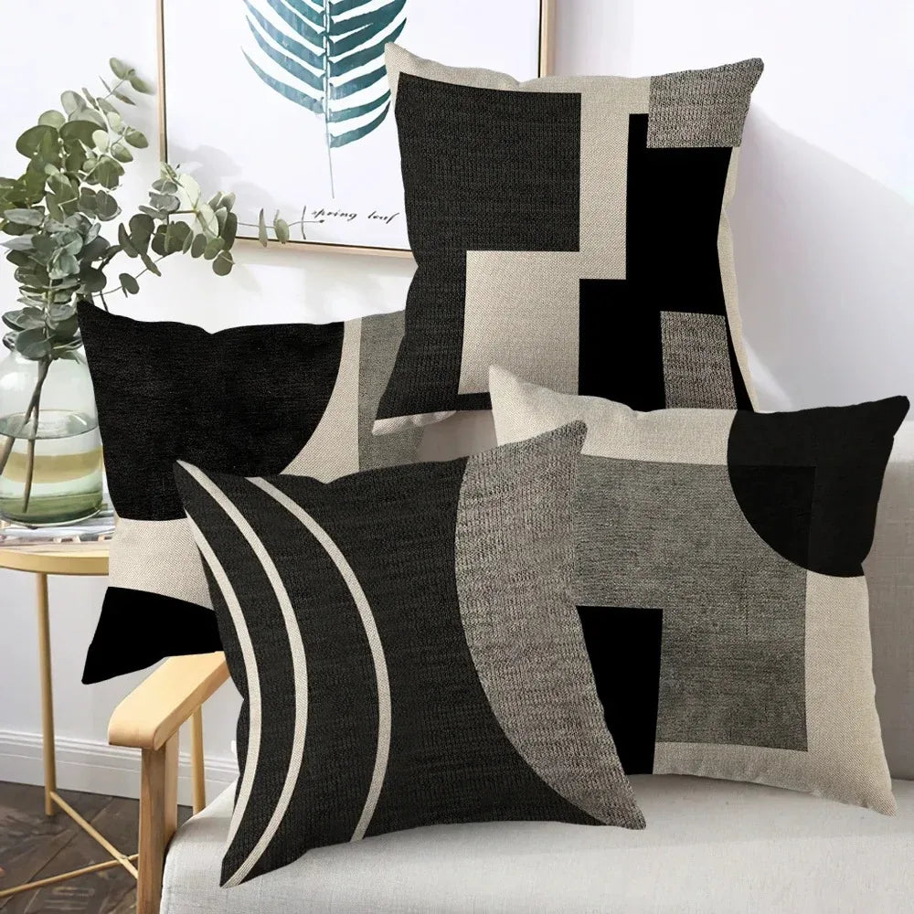 A collection of abstract geometric throw pillows in black, gray, and beige tones.