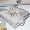 A folded light gray ice silk cooling quilt with a brass zipper visible on the top layer.