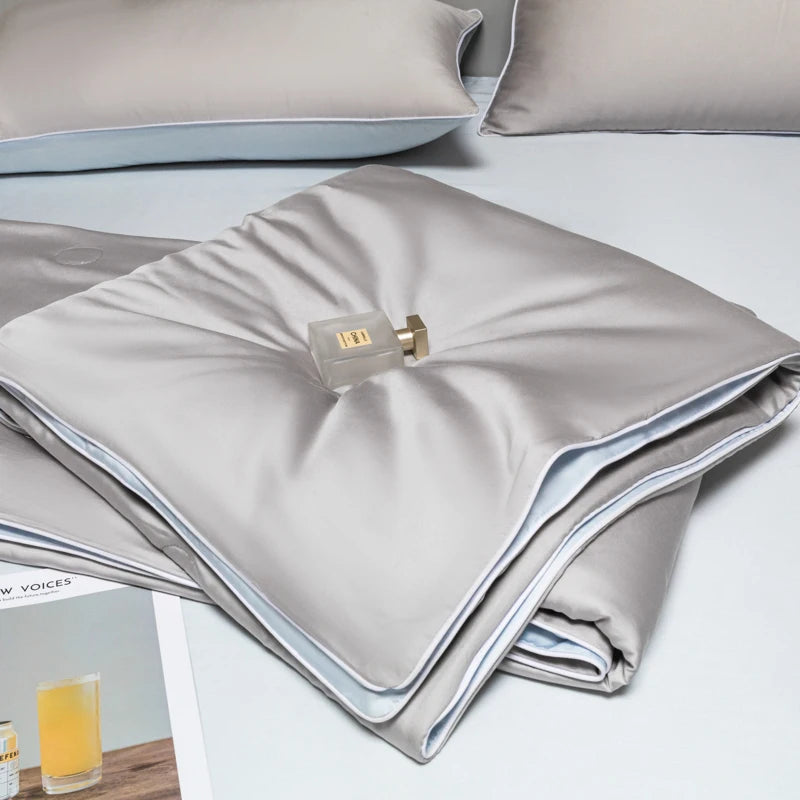 A folded light gray ice silk cooling quilt with a brass zipper visible on the top layer.
