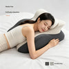 A woman is relaxing with an ergonomic memory foam wedge pillow for pain relief on a white bed.
