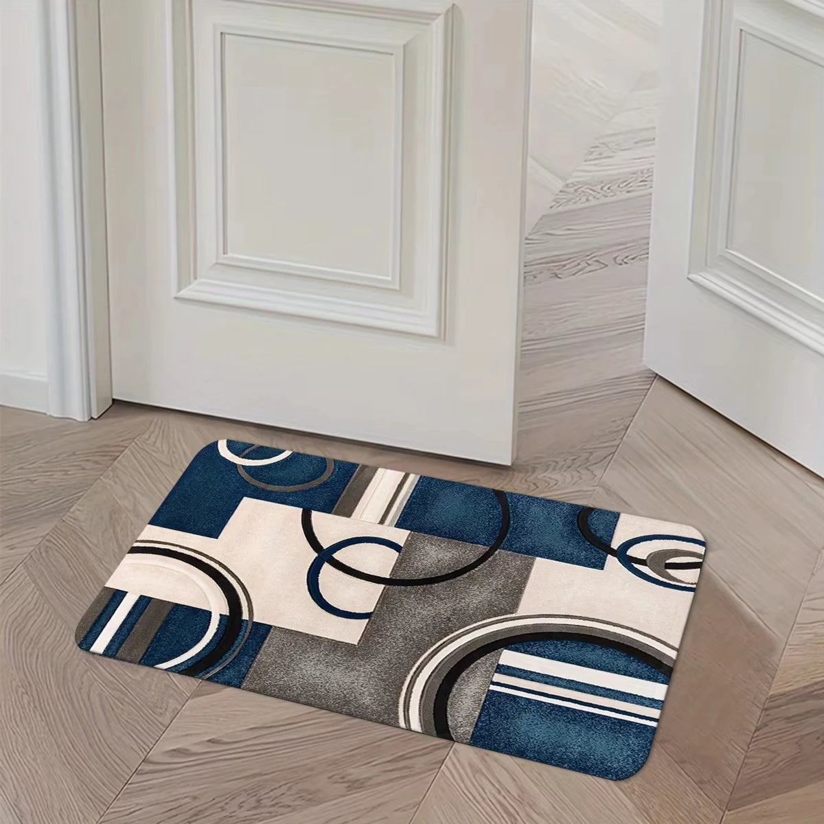 A rectangular geometric patchwork floor mat featuring blue, gray, and beige tones on a light wood floor.
