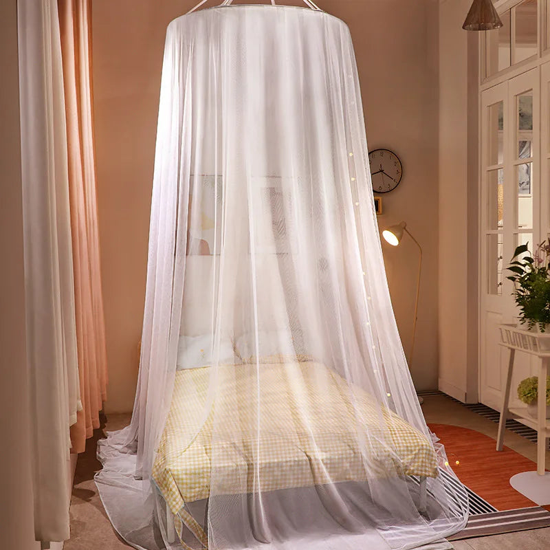 White mosquito net canopy draped over a bed in a room.
