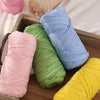 A collection of colorful reusable elastic yarn spools in pink, green, blue, and yellow resting in a wooden box.