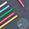 A collection of colorful needle threaders in various shades including white, blue, green, pink, and yellow against a dark bac