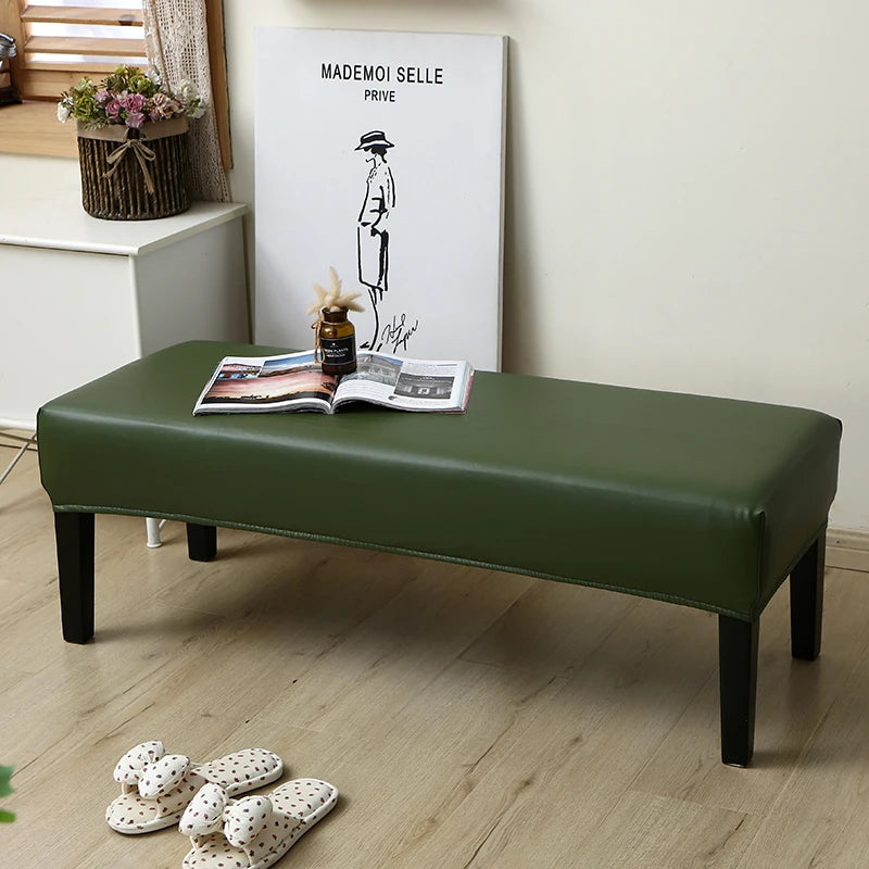 A dark green waterproof stretch dining bench cover placed on a wooden floor.
