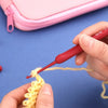 A hand is using a red crochet hook to create yellow yarn, demonstrating ergonomic crochet tools.