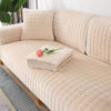 A beige quilted sofa protection cover with a matching pillow and a pink rose decoration.